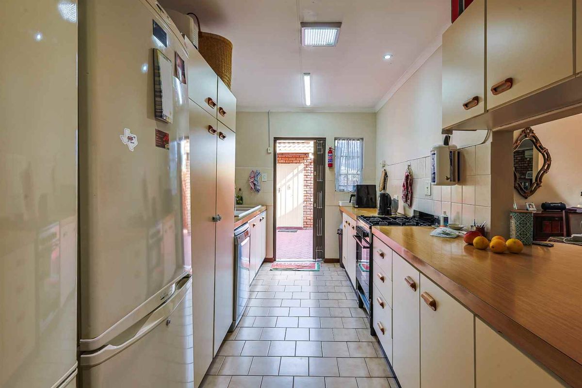 A functional galley-style kitchen featuring laminate countertops, built-in cabinetry, and direct access to an outdoor patio area.