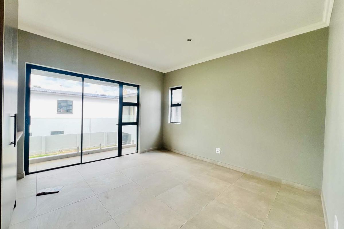 A bright, modern, and empty bedroom featuring large sliding glass doors, neutral tiled flooring, and clean finishes, ready for personalization.