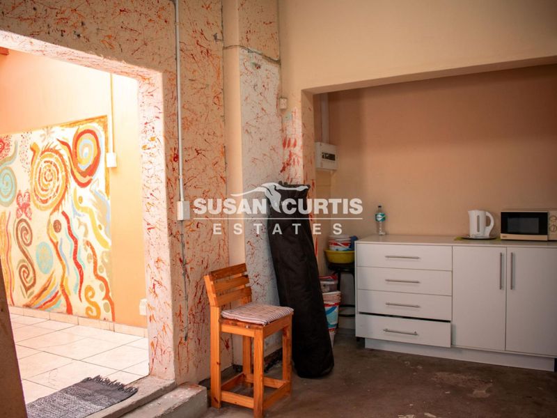 A small kitchen area featuring basic built-in cabinetry and an electrical distribution board, currently requiring significant wall and flooring renovation to improve functionality.