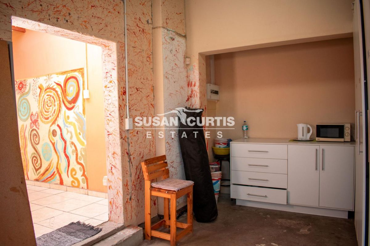 A small kitchen area featuring basic built-in cabinetry and an electrical distribution board, currently requiring significant wall and flooring renovation to improve functionality.