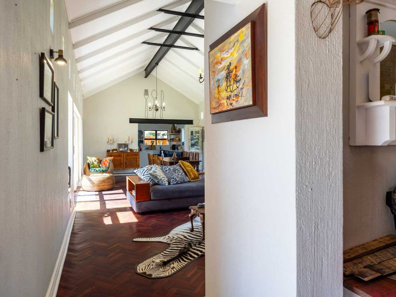 Spacious open-plan living area featuring a high vaulted ceiling with exposed steel beams and classic herringbone parquet flooring.