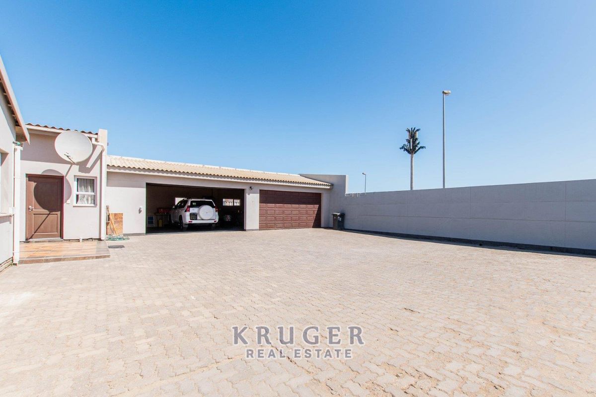 Spacious paved rear courtyard area featuring a large garage and secure boundary walling.
