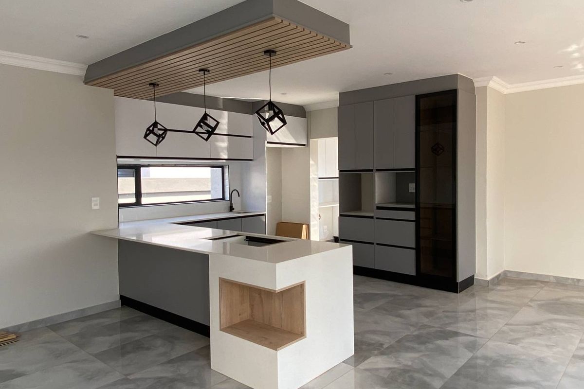 Modern, newly renovated kitchen featuring sleek grey cabinetry, a central island with quartz countertops, and a stylish slatted timber ceiling detail.
