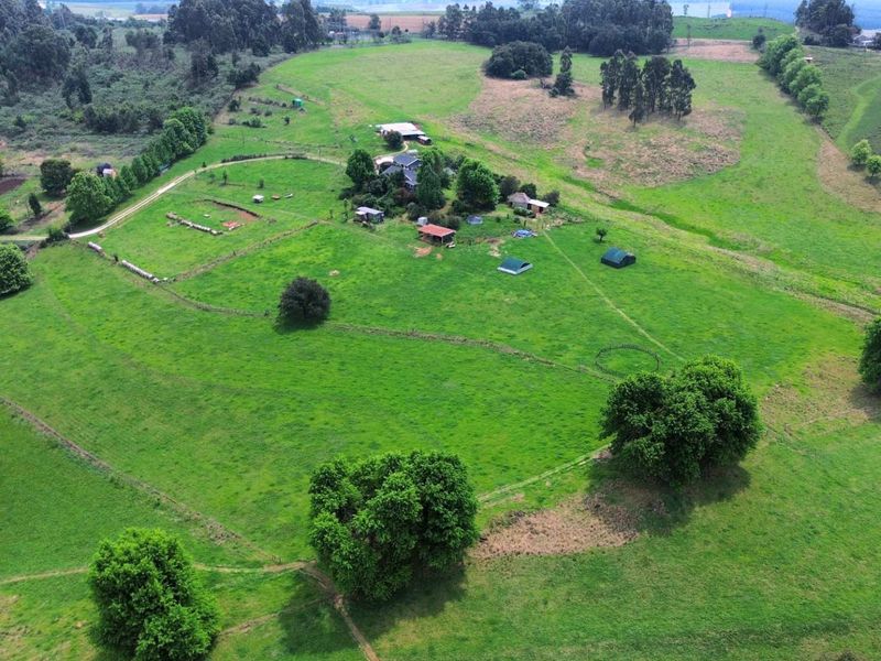 Aerial view of a large small holding property featuring expansive green paddocks, multiple outbuildings, and established trees across the landscape.