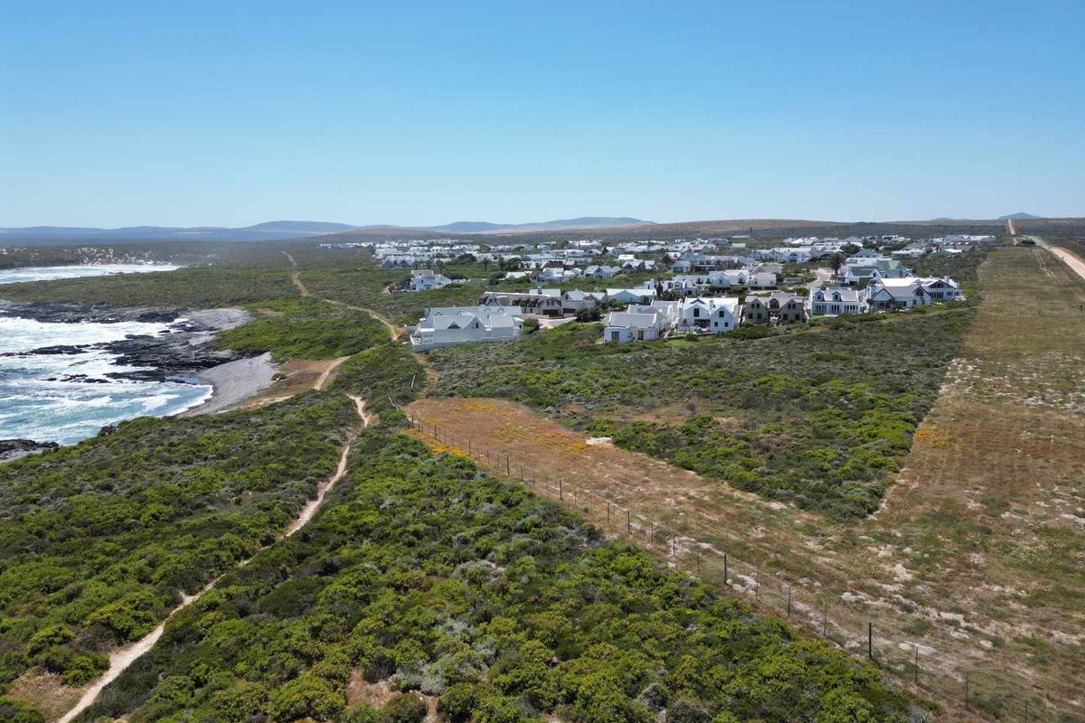 Aerial view of a coastal residential development featuring natural vegetation, coastal access paths, and proximity to the ocean.