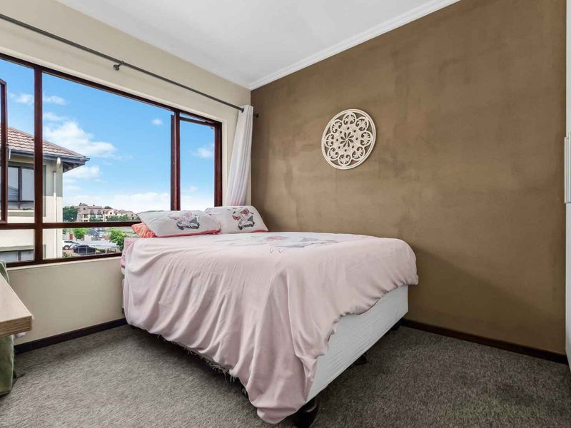 A bedroom featuring a large window with natural light, carpeted flooring, a built-in wardrobe, and a dark accent wall.