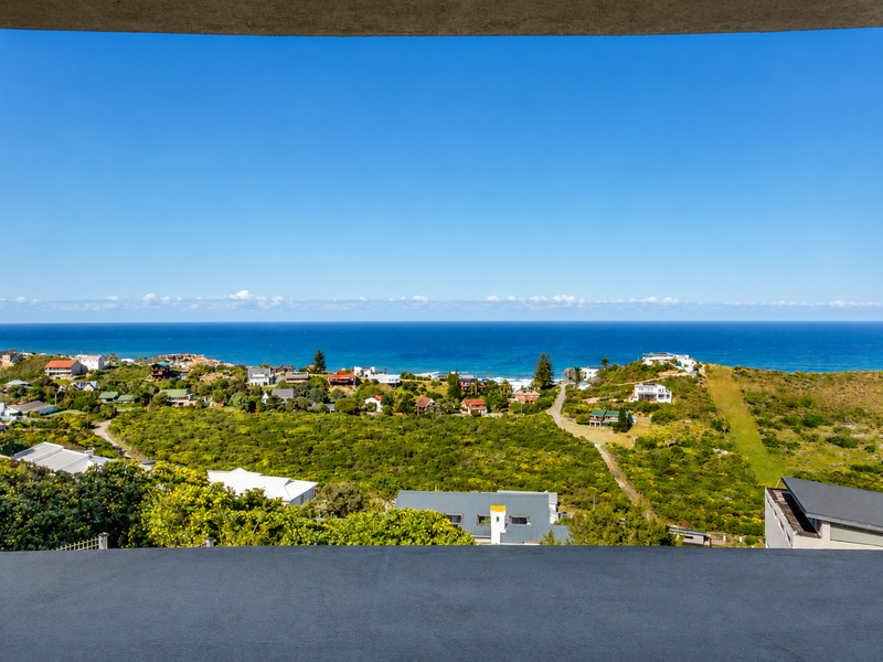 A clear, elevated view of the coastal landscape and ocean, framed by a concrete balcony structure.