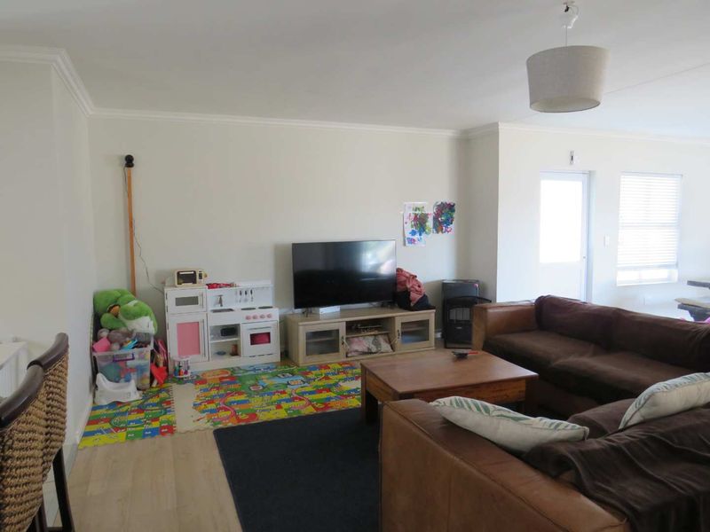 A spacious living room featuring neutral walls, coving, and laminate flooring, providing a versatile area for family relaxation.