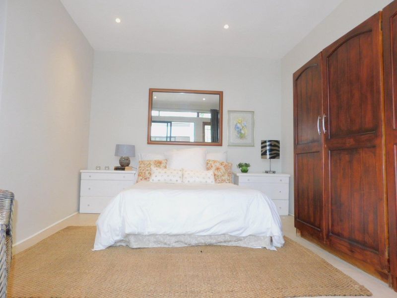 A well-maintained bedroom featuring neutral walls, recessed downlighting, and a large built-in wooden wardrobe.