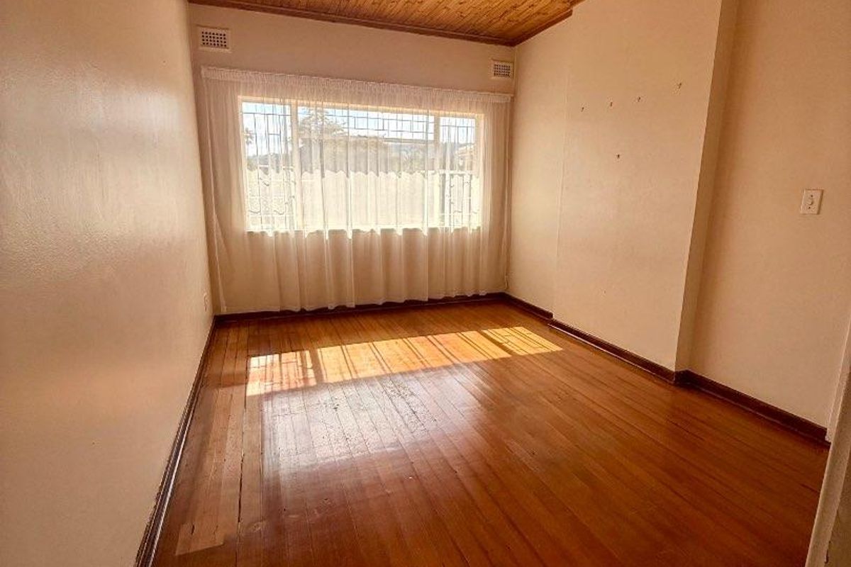A vacant bedroom featuring polished timber flooring and a natural timber ceiling, providing a neutral canvas for potential interior updates.