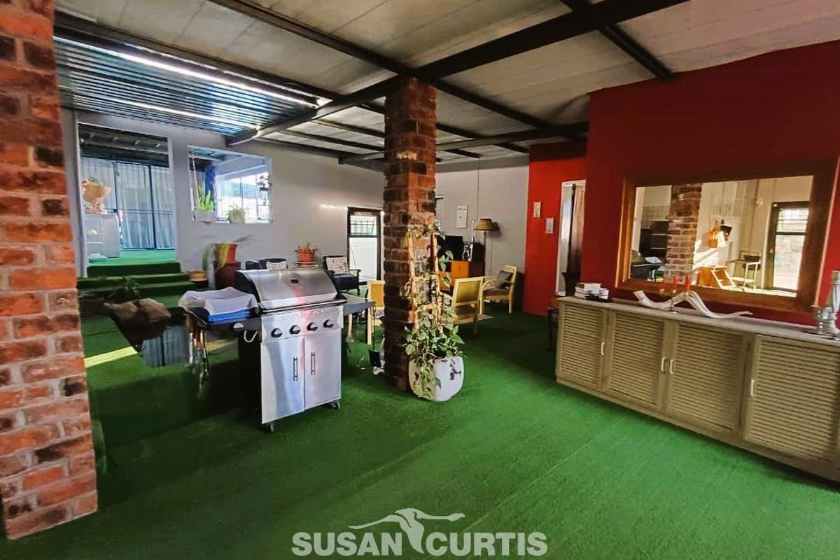 An expansive, multi-level indoor entertainment area featuring exposed brick pillars, industrial-style ceiling, and artificial turf flooring, suitable for a versatile recreational space.