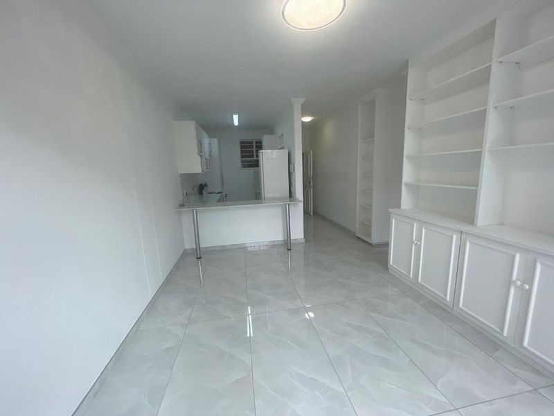 Bright open-plan living area featuring modern tiled flooring, built-in cabinetry, and a functional breakfast bar connecting to the kitchen space.