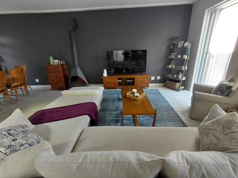 Spacious living room featuring tiled flooring, a modern freestanding fireplace, and large sliding glass doors providing natural light.