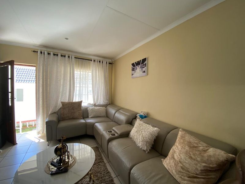 A comfortable living room featuring tiled flooring and a sliding glass door providing access to the exterior.