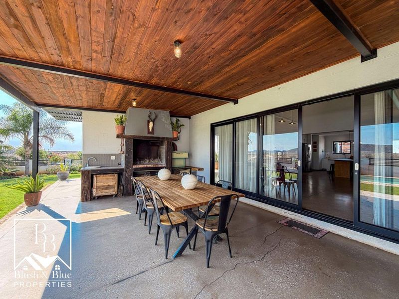Covered patio featuring a built-in braai, timber ceiling, and sliding glass doors providing seamless access to the interior living space.