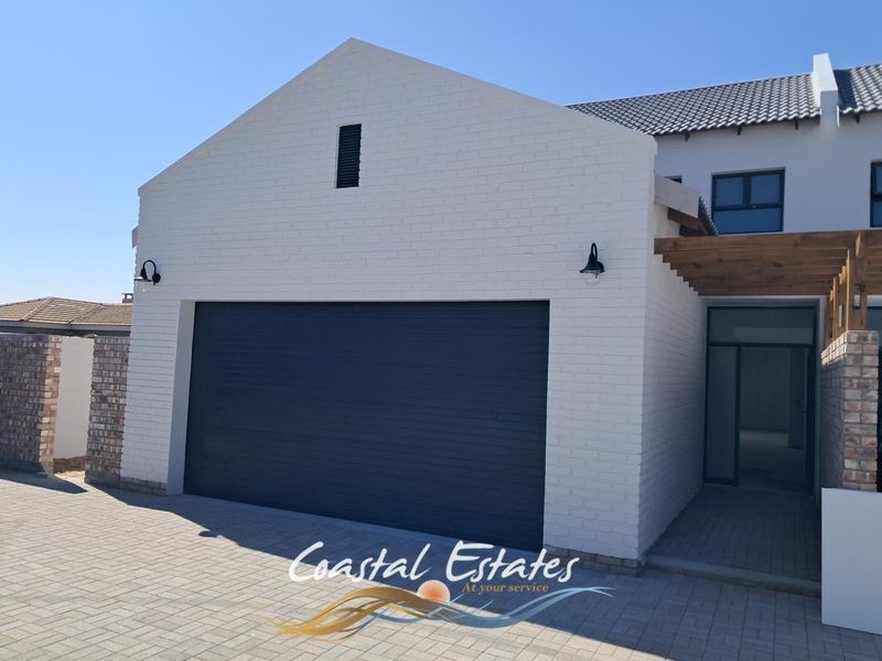 Modern townhouse exterior featuring a clean white brick facade, a double garage, and a timber pergola entrance.