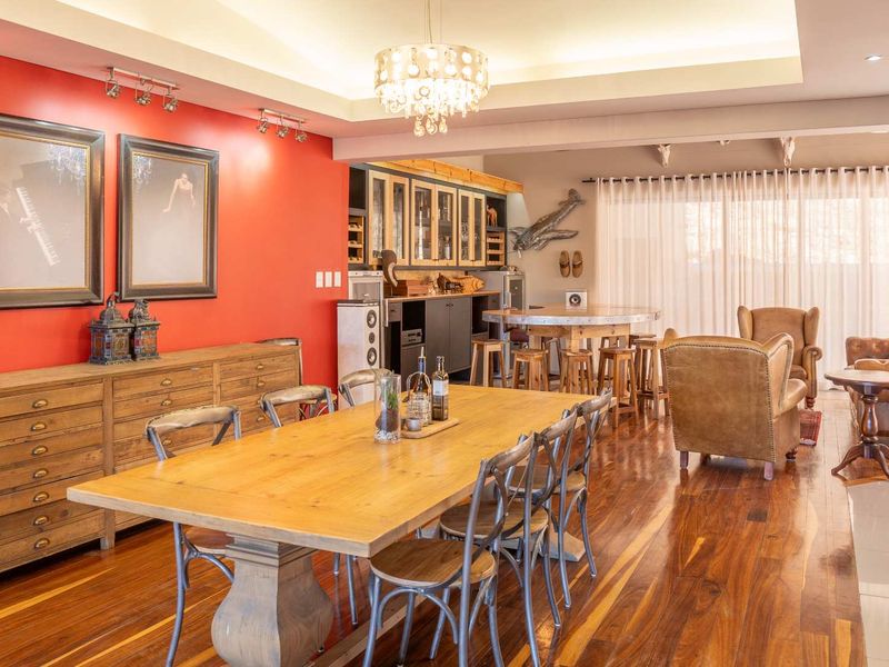 Spacious open-plan living and dining area featuring rich hardwood flooring, a coffered ceiling with recessed lighting, and a dedicated built-in bar section.