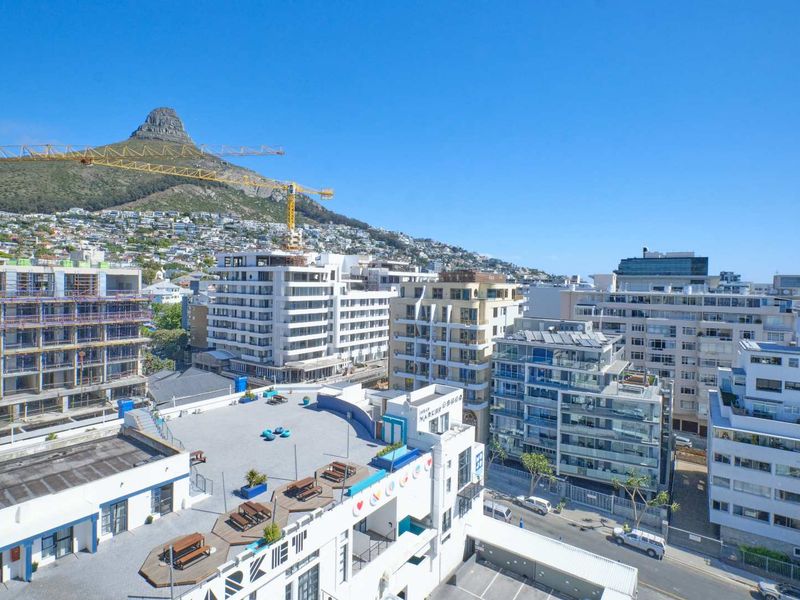 An elevated urban view overlooking surrounding apartment buildings and city streets with a prominent mountain backdrop.
