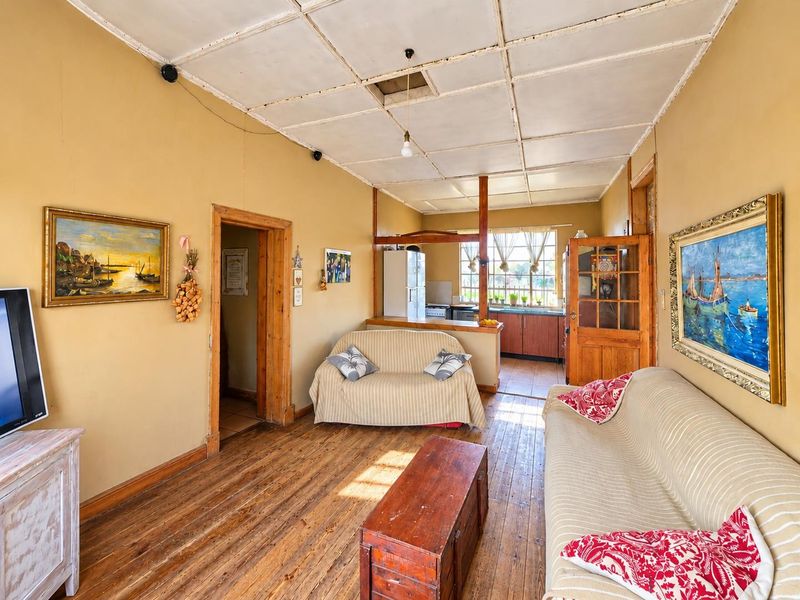 Open plan living area featuring original timber flooring and a connected kitchen space with wooden cabinetry and a breakfast counter.