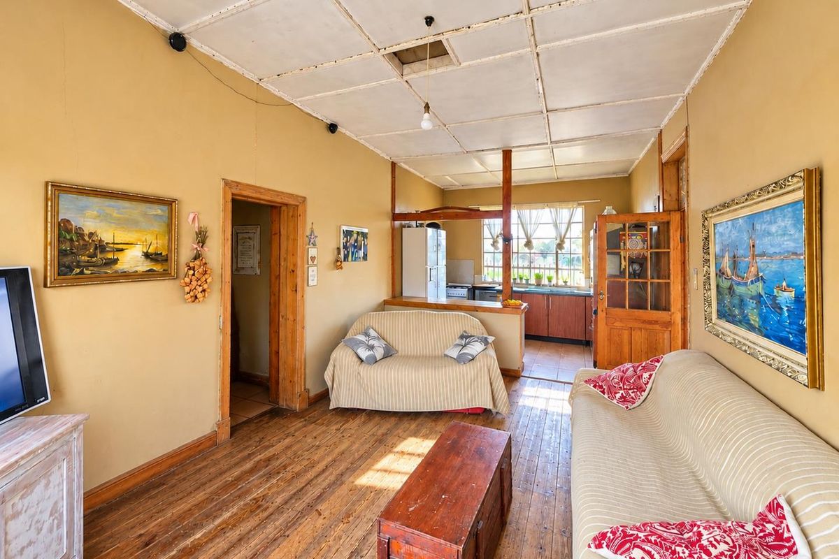 Open plan living area featuring original timber flooring and a connected kitchen space with wooden cabinetry and a breakfast counter.
