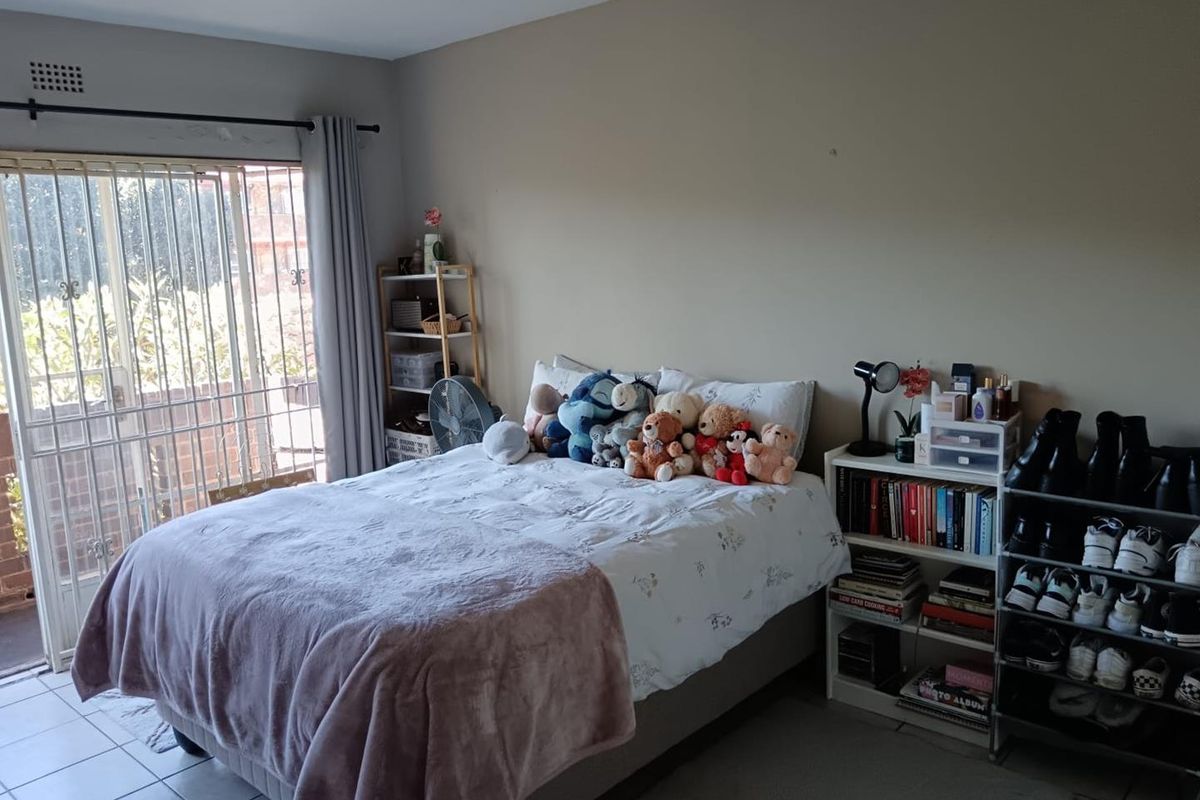A bedroom featuring tiled flooring and a sliding glass door with security gate providing access to an outdoor area.
