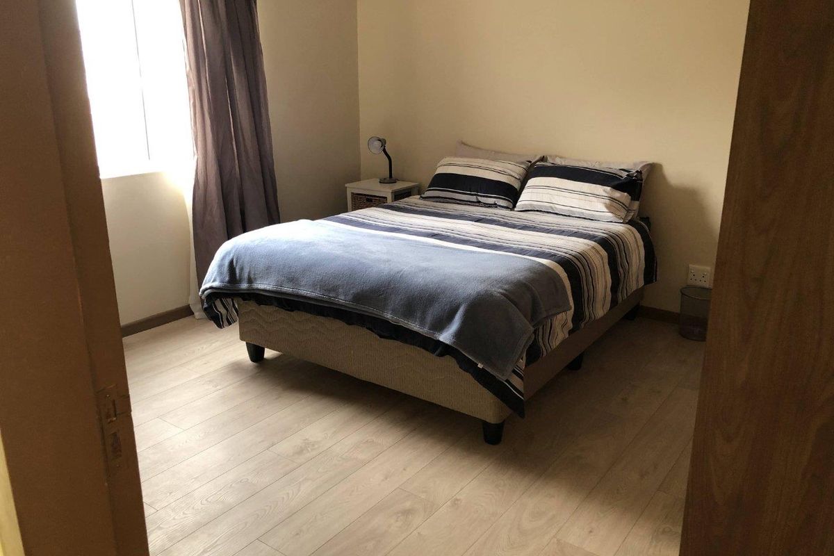 A well-lit bedroom featuring light-toned laminate flooring and neutral wall finishes, providing a comfortable and functional living space.