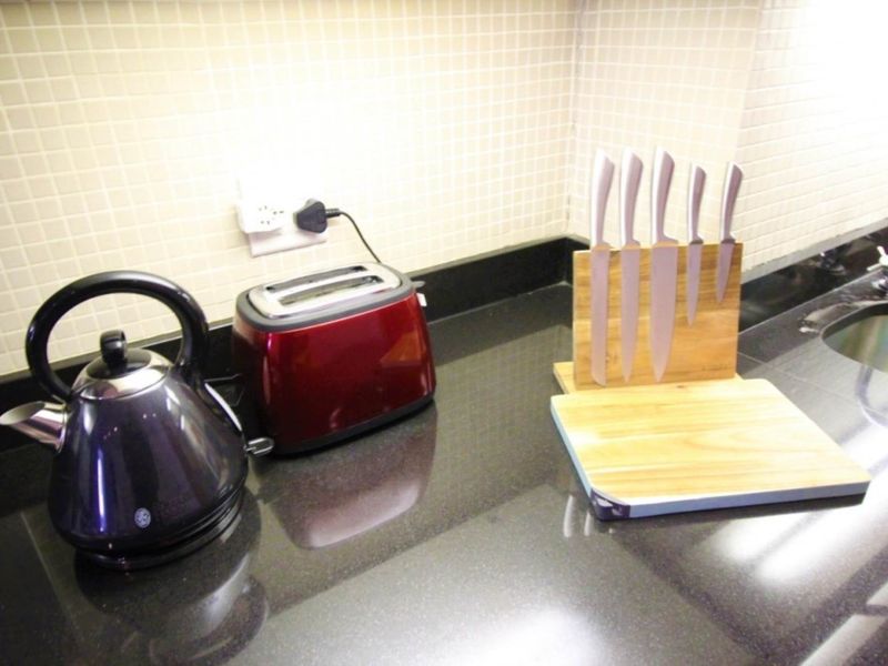 A functional kitchen workspace featuring a polished black granite countertop, a mosaic tile backsplash, and an integrated undermount sink.