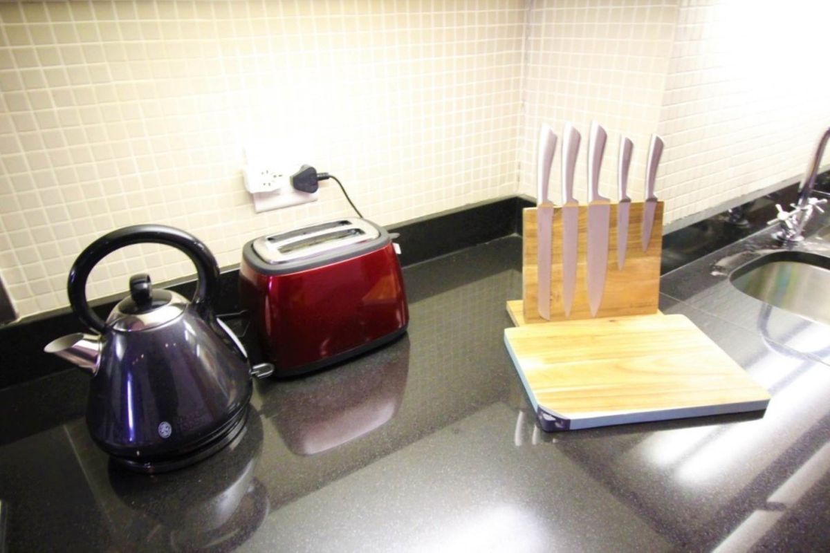 A functional kitchen workspace featuring a polished black granite countertop, a mosaic tile backsplash, and an integrated undermount sink.
