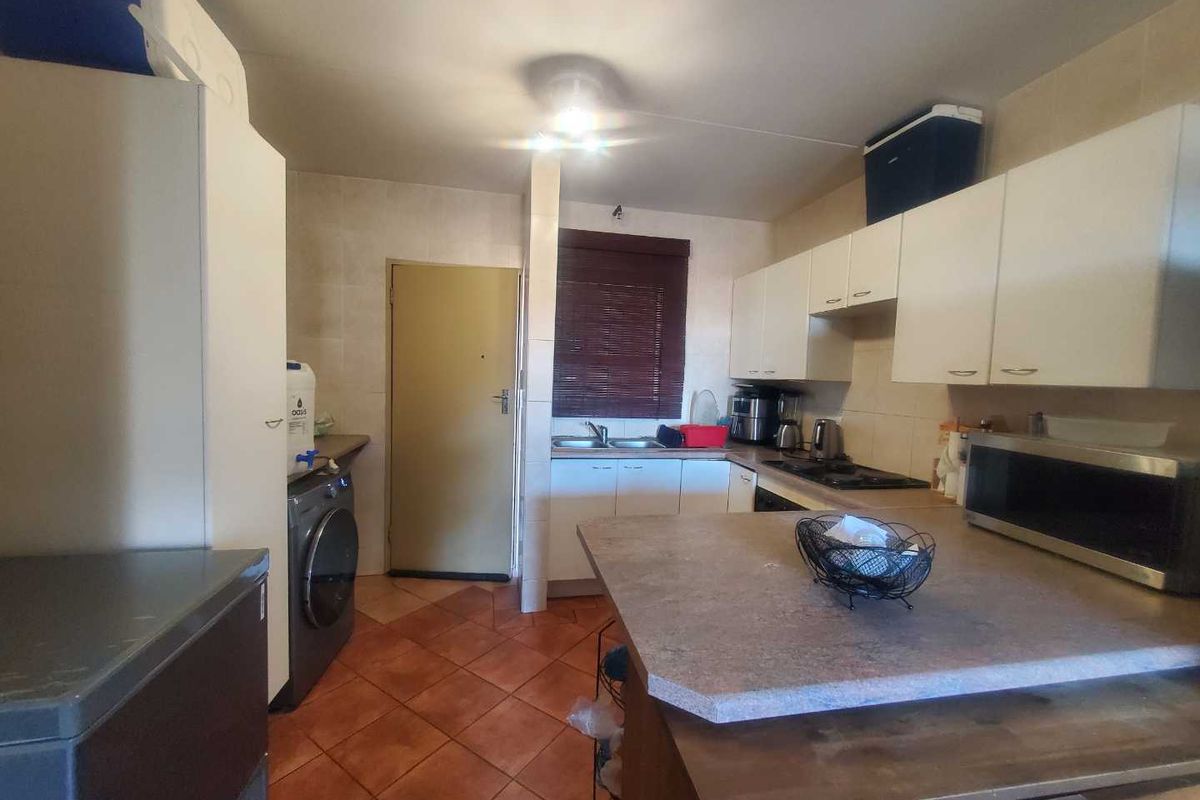 Functional kitchen featuring built-in cabinetry, integrated hob, double sink, and dedicated laundry area with tiled flooring.