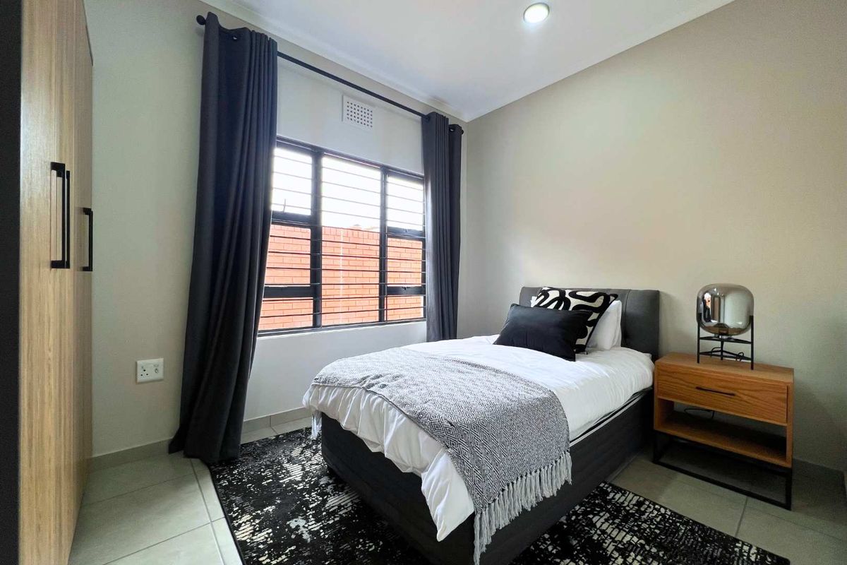 A well-maintained bedroom featuring neutral wall tones, tiled flooring, and a built-in wardrobe, offering a clean and functional living space.