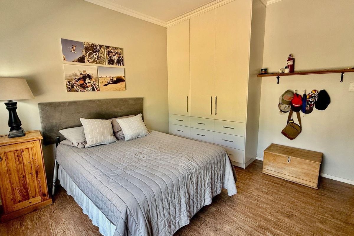 A bedroom featuring built-in floor-to-ceiling wardrobes, wood-look flooring, and crown molding, providing functional storage and a neutral living space.