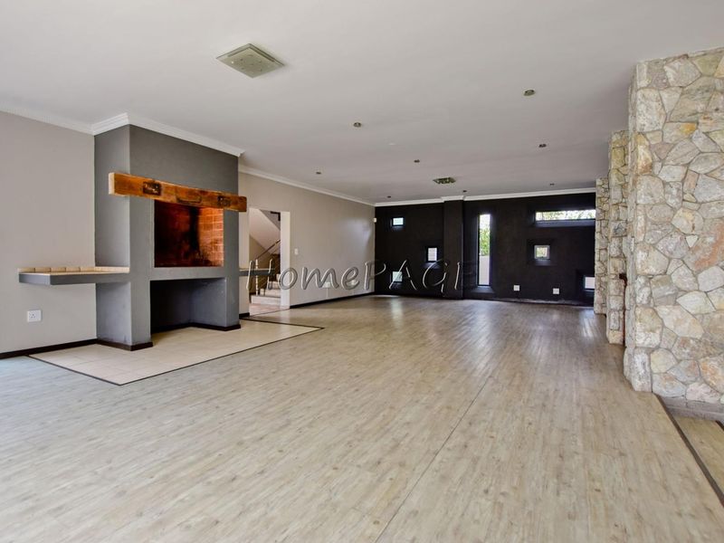 Spacious open-plan living area featuring a built-in fireplace, stone cladding accents, and modern laminate flooring throughout.