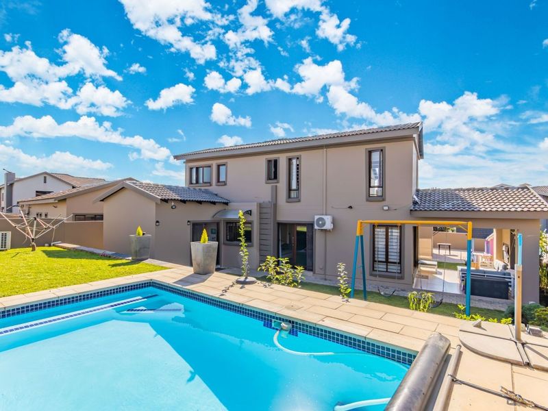 Rear view of the cluster home featuring a private swimming pool, paved patio area, and well-maintained garden space.