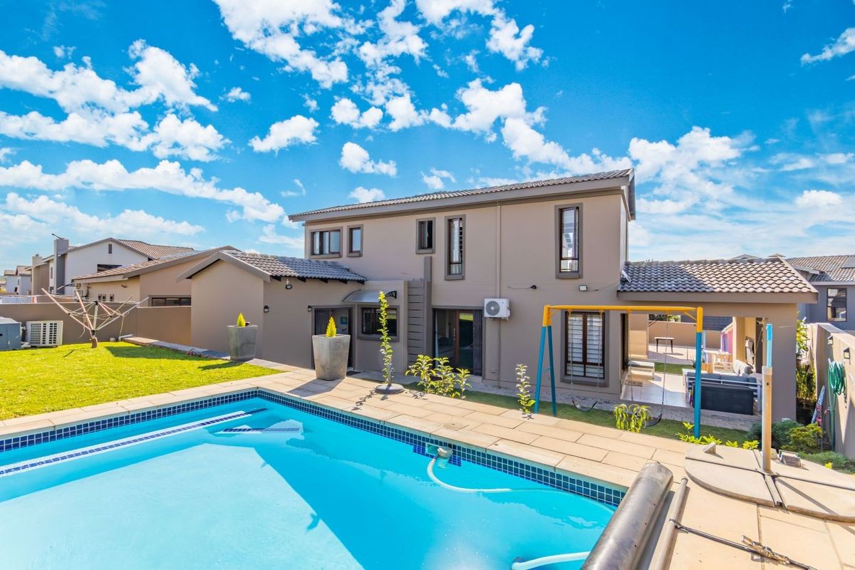 Rear view of the cluster home featuring a private swimming pool, paved patio area, and well-maintained garden space.