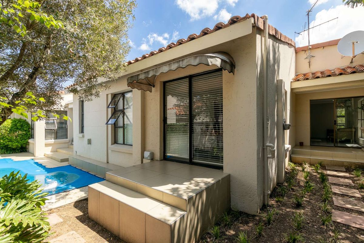 Rear exterior view featuring a tiled patio area, sliding glass doors, and direct access to the swimming pool.