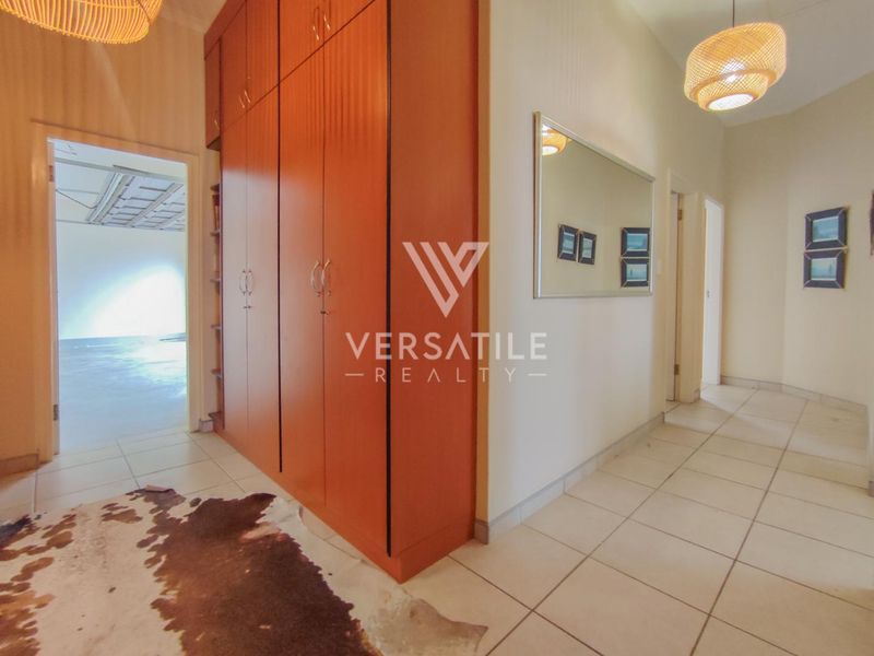 A functional hallway featuring tiled flooring and extensive built-in storage cupboards, providing practical access to adjacent rooms within the townhouse.