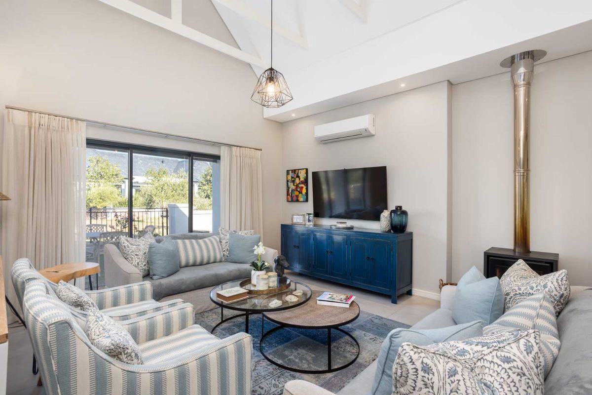 Spacious living room featuring high vaulted ceilings, a modern fireplace, split-system air conditioning, and large sliding glass doors leading to the patio.