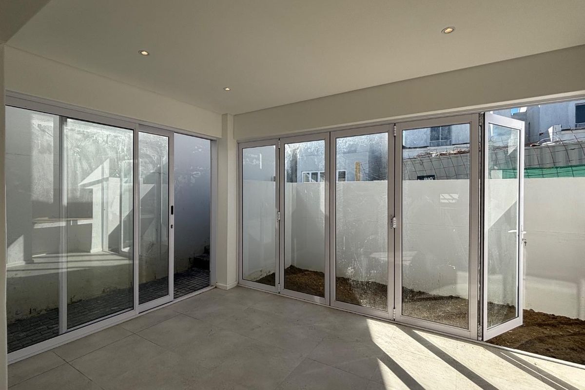 Bright, modern living area featuring large glass sliding and folding doors that open directly onto a private courtyard space.