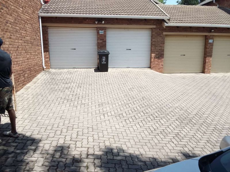 Exterior view of a townhouse complex featuring brick facade garages with roll-up doors and a paved driveway area.