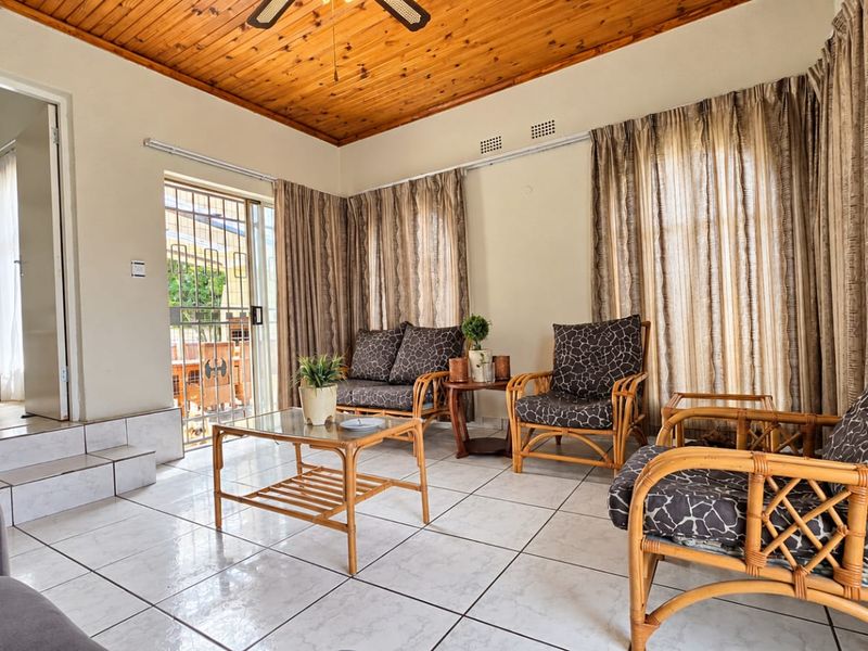 A living room featuring ceramic floor tiles, a timber tongue and groove ceiling, and a sliding glass door with security gate access to the exterior.