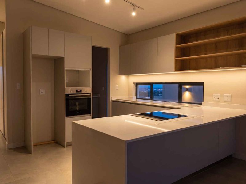 Modern kitchen featuring sleek cabinetry, quartz countertops, integrated oven and hob, and ambient under-cabinet lighting in a clean, contemporary design.