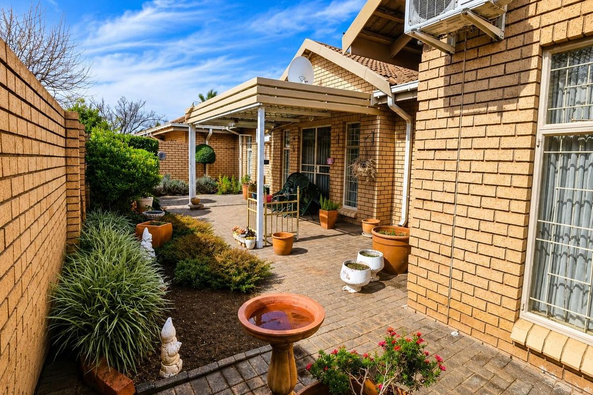 A well-maintained rear courtyard featuring brick paving, a covered patio area, and a brick boundary wall, providing a private outdoor space.