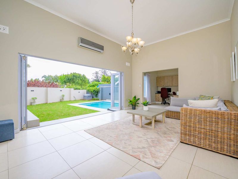 Spacious living area featuring large stacking doors that open onto a private garden and swimming pool, with an adjoining study nook.