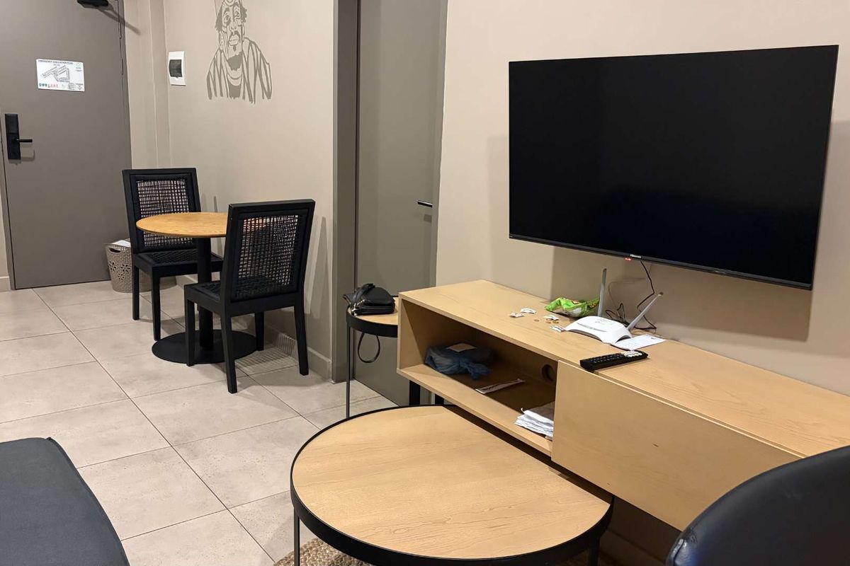 A functional living area featuring tiled flooring, neutral wall tones, and a wall-mounted television setup.