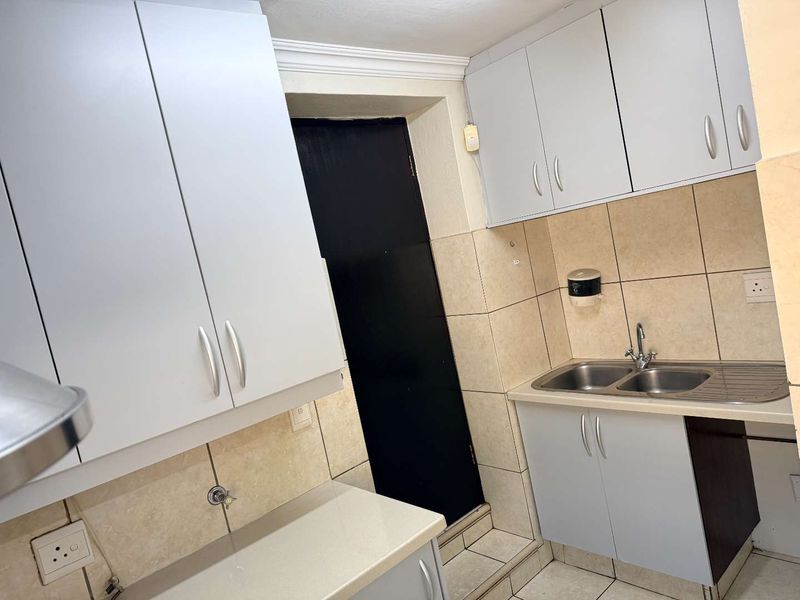A functional scullery area featuring built-in cabinetry, a double stainless steel sink, and tiled finishes, providing practical utility space.