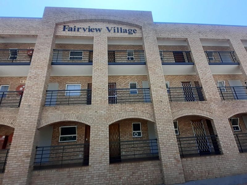 Front elevation of Fairview Village apartment complex featuring face brick construction, multiple levels with private balconies, and secure metal railings.