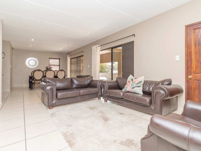 Spacious open-plan living and dining area featuring neutral tiled flooring, recessed lighting, and sliding glass doors leading to an outdoor patio.