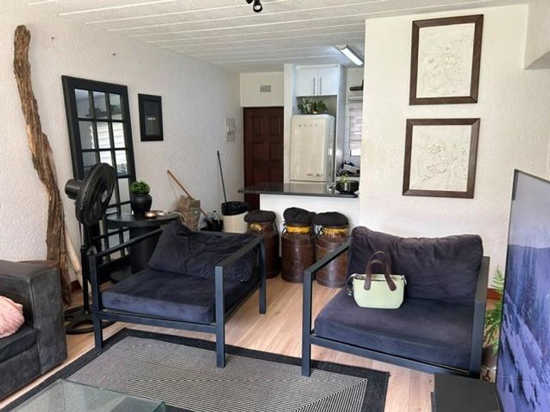 Open plan living area featuring a breakfast bar, laminate flooring, and integrated kitchen cabinetry, offering a functional layout for modern apartment living.
