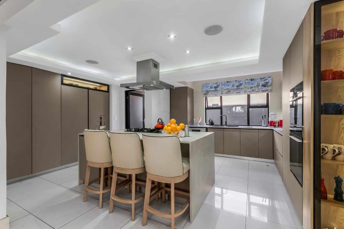 Modern kitchen featuring a central island, built-in appliances, sleek cabinetry, recessed lighting, and polished tiled flooring.