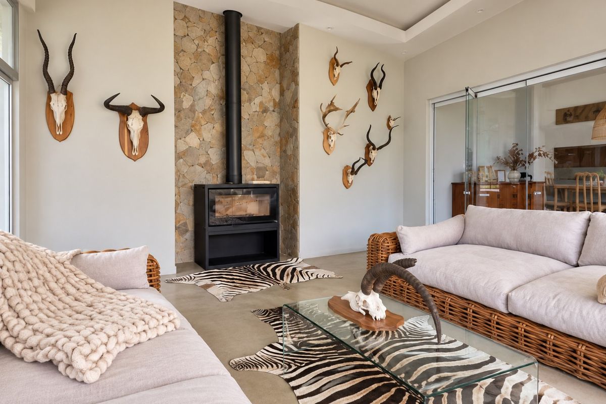 A modern living room featuring a striking stone-clad fireplace, polished concrete floors, and recessed ceiling lighting, creating a warm and inviting atmosphere.